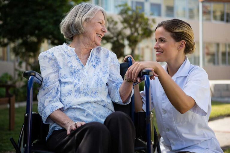 Older adults and a family member reviewing care notes together in a bright assisted living apartment.