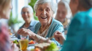 Older adults share a balanced meal at a bright assisted living dining table with water and colorful vegetables.