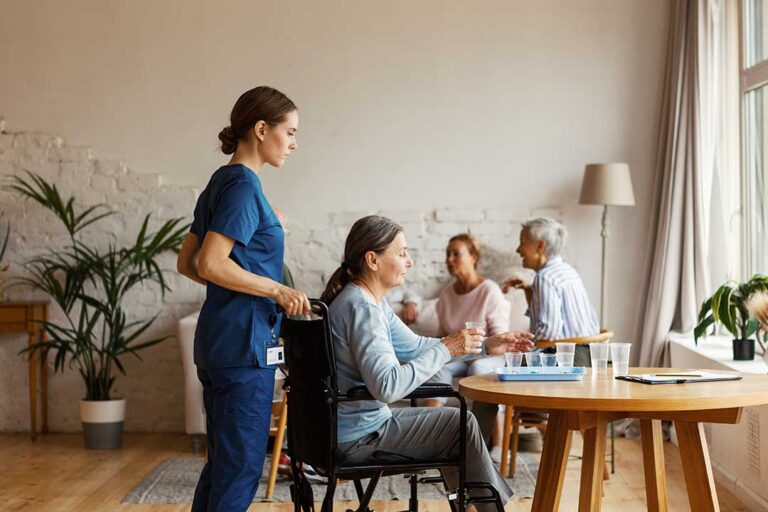 Older adults play cards and complete crafts together in a bright assisted living activity room.
